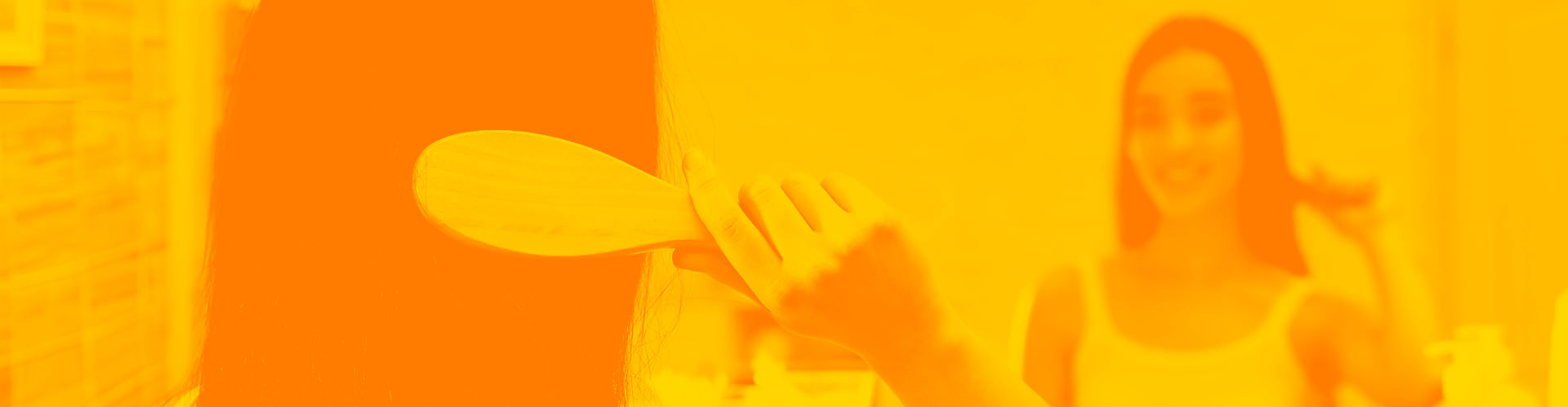 Stylized orange image of woman brushing her hair in the mirror